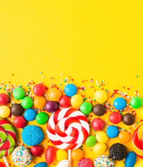 Colorful candies over yellow background. Top view. Flat lay. Copy space. Sweet mix for birthday or candy shop