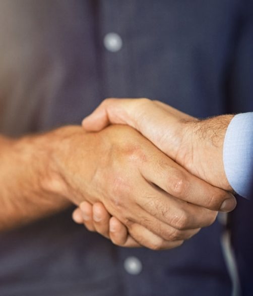 Close up of friendly handshake of business people. Business partners signing deal with handshake at office. Negotiation meeting for a successful merger, business agreeement.