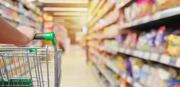 shopping cart in supermarket aisle with product shelves interior defocused blur background