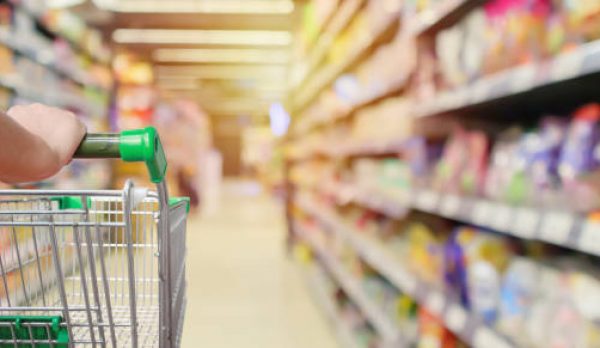 shopping cart in supermarket aisle with product shelves interior defocused blur background